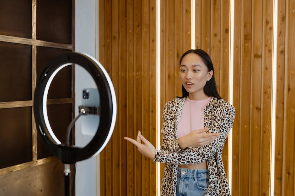 Young Asian woman recording a vlog with a ring light indoors, wearing leopard print.